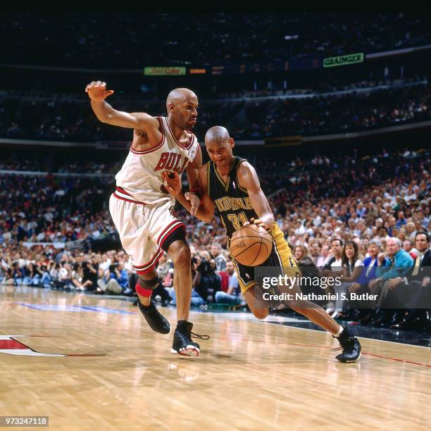 Reggie Miller of the Indiana Pacers drives against Ron Harper of the Chicago Bulls during a game played on May 19, 1998 at the United Center in...