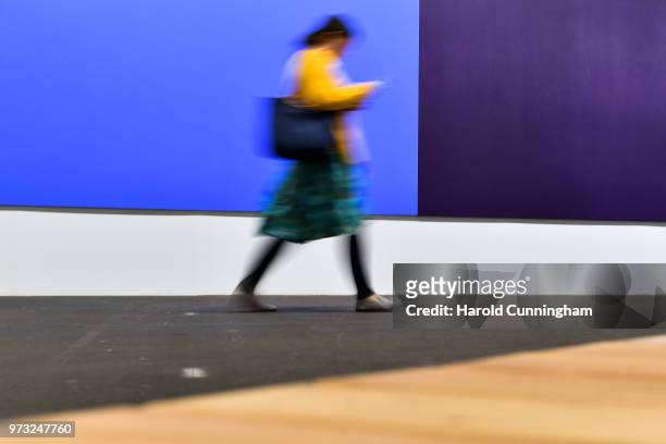 Visitor walks past the artwork of Olivier Mosset "Untitled" during the press preview for Art Basel at Basel Messe on June 13, 2018 in Basel,...