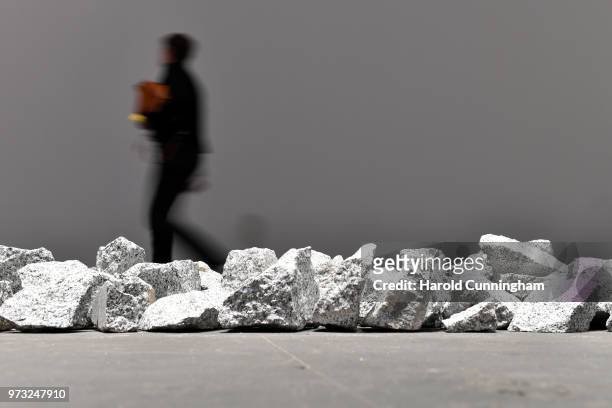 Visitor walks past the artwork of Richard Long "Ivory Granite Line" during the press preview for Art Basel at Basel Messe on June 13, 2018 in Basel,...