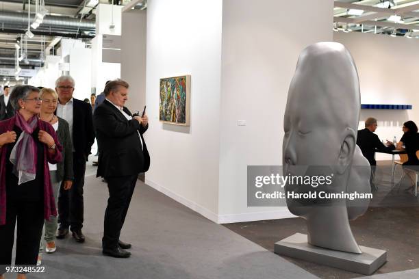 Visitor takes a photo of the artwork of Jaume Plensa "Mar" during the press preview for Art Basel at Basel Messe on June 13, 2018 in Basel,...