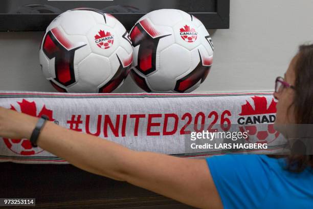 An employee holds up a scarf with the hashtag for World Cup in 2026 at Soccer Canada Headquarters in Ottawa, Ontario on June 13 as Canada will...