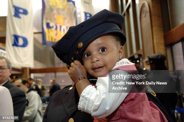 Nine-month-old Samantha Stewart wears a police officer's cap after a ceremony honoring her father, Detective Dillon Stewart, and two other officers...