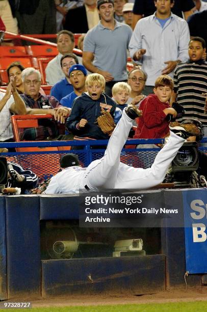 New York Mets' David Wright dives into the photo box to snag a foul pop, much to the delight of one young Met fan, in the second inning of game...