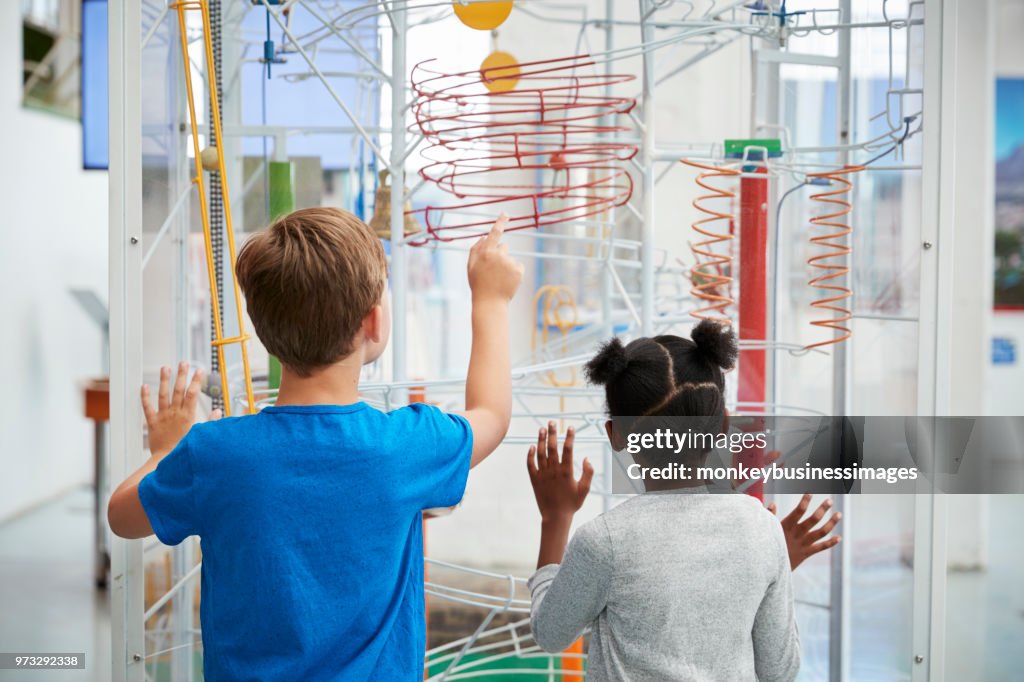 Two kids looking at a science exhibit,  back view