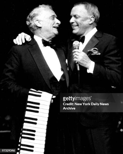 Victor Borge, holding piano keyboard scarf, frolics with Frank Sinatra on stage at Radio City Music Hall.