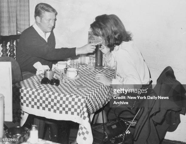 Mike Nichols lights a cigarette for Jacqueline Kennedy at Right Bank restaurant.