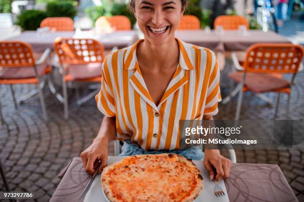 feliz mujer comiendo una pizza. - naranja color fotografías e imágenes de stock