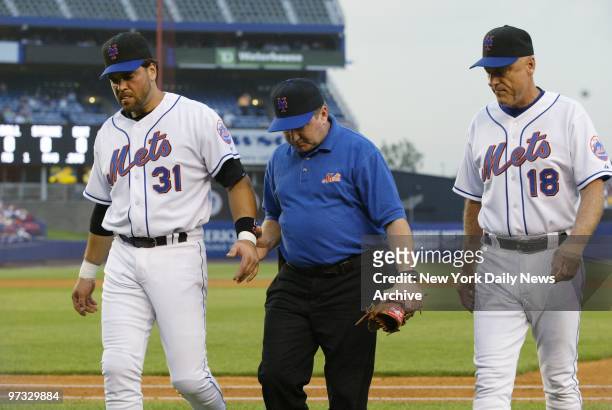 New York Mets' first baseman Mike Piazza walks off the field accompanied by trainer Scott Lawrenson and manager Art Howe after colliding with the...
