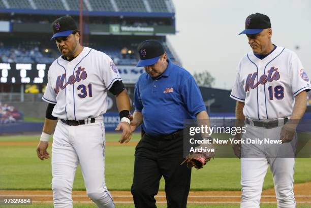 New York Mets' first baseman Mike Piazza walks off the field accompanied by trainer Scott Lawrenson and manager Art Howe after colliding with the...