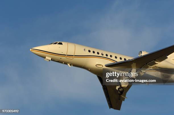 A Dassault Falcon 900EX climbing out after take-off with undercarriage retracting.