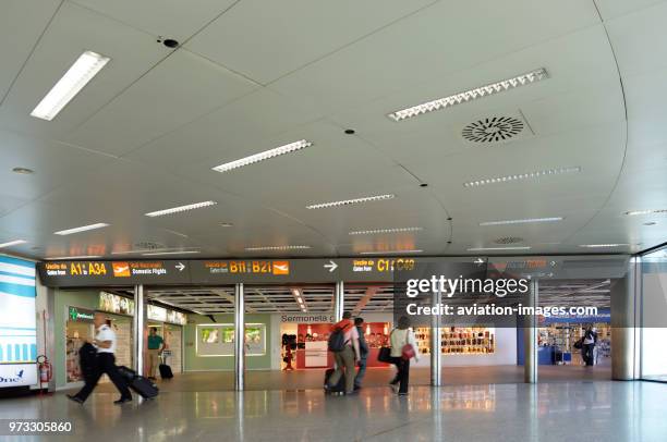Passengers walking in the terminal with sign for gates A1-A34, B11-B21, C1-C49, way out to Roma and baggage claim in English and Italian languages.