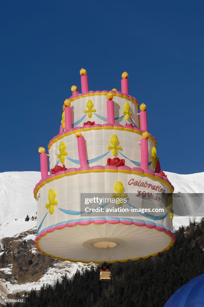 A Lindstrand Cake special-shape hot-air balloon flying with trees