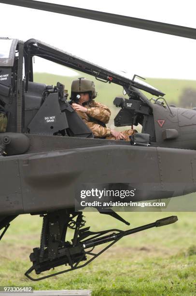 Pilot wearing helmet in the cockpit of a British Army Air Corps Boeing WAH-64D Apache AH-1 with 30 millimetre chain-gun parked on the grass at the...