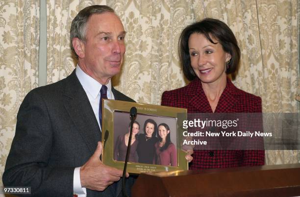 With his former wife, Susan Brown, smiling at his side, Mayor Michael Bloomberg holds a photo of her and their daughters, Emma and Georgina. They...