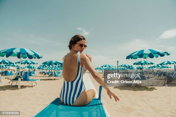 junge frau, die italienischen strand sunscreeen gefährden - suntan lotion stock-fotos und bilder