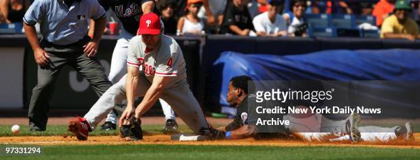 New York Mets' Jose Reyes slides into third on a triple as the ball gets by Philadelphia Phillies' David Bell in sixth inning action at Shea Stadium....
