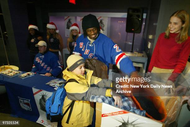 The New York Rangers' Dan LaCouture and Anson Carter look on as Kevin Rubin of Brooklyn, makes a donation to the New York Cares Coat Drive at the...