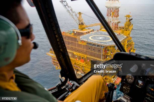 helicopter approaches a drilling rig - sikorsky helicopter stock pictures, royalty-free photos & images