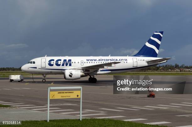 A national arrivals sign in the French and English languages with a CCM Compagnie Corse Mediteranee Airbus A319-100 parked behind.