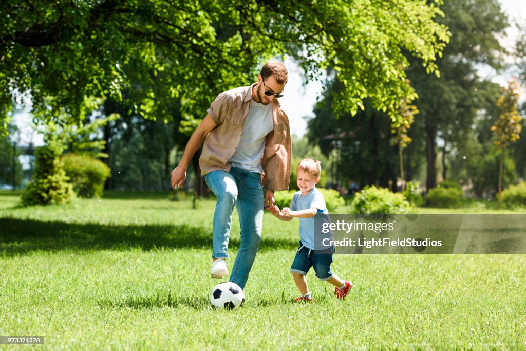 Dad and son playing football at park