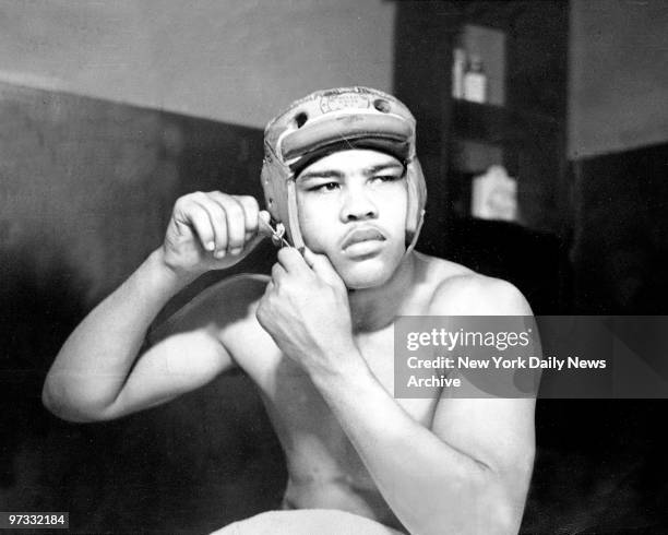 The 21-year-old Joe Louis adjusts his head protector before taking on his sparring partners.