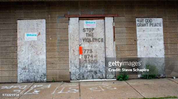 View of boarded-up doorways set into a wall, Chicago, Illinois, June 10, 2018. The doors feature graffiti that reads, in part, 'Stop the Violence'...