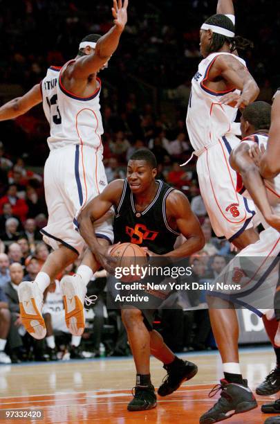 Oklahoma State Cowboys' Obi Muonelo splits two Syracuse Orange defenders on his way to the basket during the first half of Game 1 of the Jimmy V...