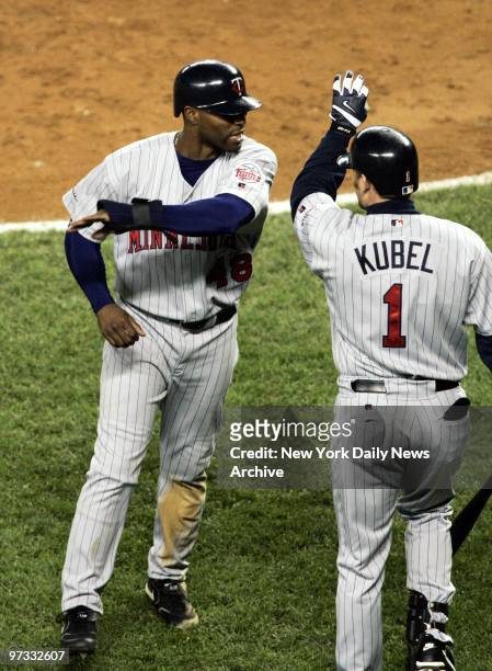Minnesota Twins' Torii Hunter gets a high five from Jason Kubel after scoring the tying run in the eighth inning of Game 2 of the American League...