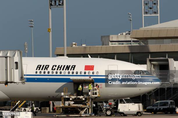 The Air China International CA CCA Airbus A340-313X parked at the terminal with baggage vehicles.