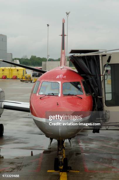 Windshield and nosewheel undercarriage of a Northwest Airlink - Mesaba Airlines Saab SF-340B+ parked with jetway extended.