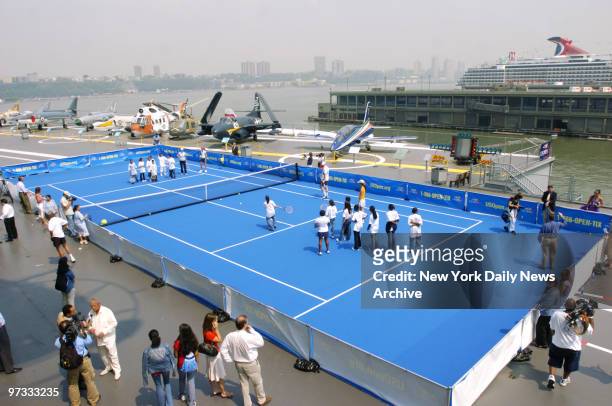 Tennis greats Monica Seles and Mary Jo Fernandez hit some balls with children at a tennis court on the deck of the Intrepid Sea-Air-Space Museum to...