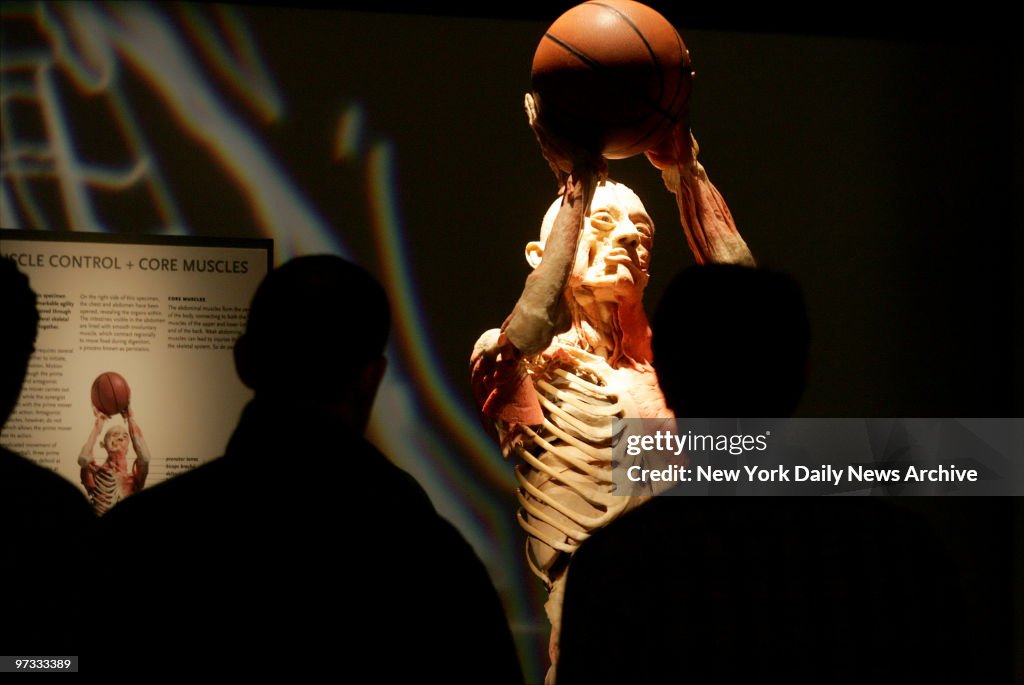 Visitors gather around a body posed as though it's playing b