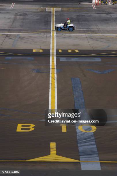 Gate B10 taxiway centreline markings with a tug crossing the apron.