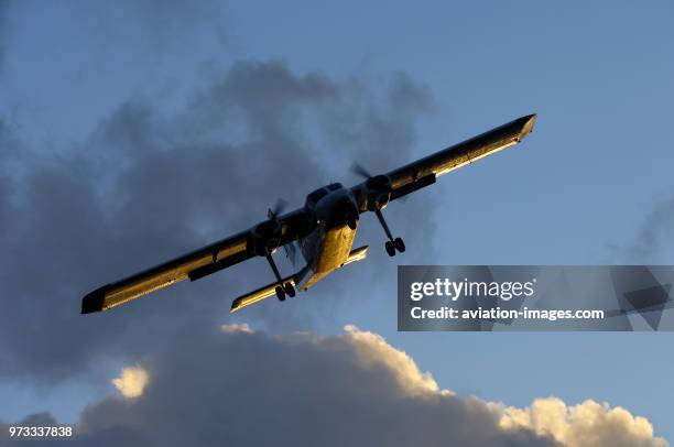 Sun glinting off the fuselage and wings with dark clouds behind.