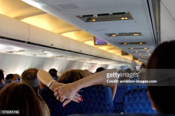 Woman stretching her arms over the headrest in the economy-class cabin seats of an American Airlines Boeing 757-200 enroute SJU-MIA on flight-number...