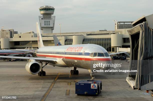 An American Airlines Boeing 757-200 being pushed-back by a tug with the air-traffic control-tower behind.
