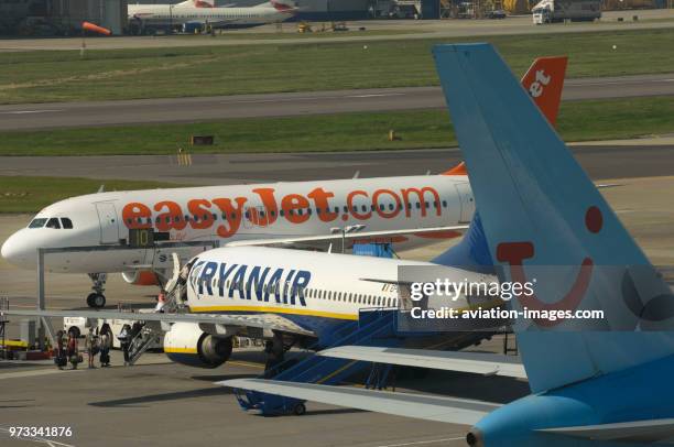 Tail of a Thomsonfly.com Boeing 767-304 ER, a Ryanair 737-800 with Servisair airstairs parked on the apron and an easyJet Airbus A319-100 behind.