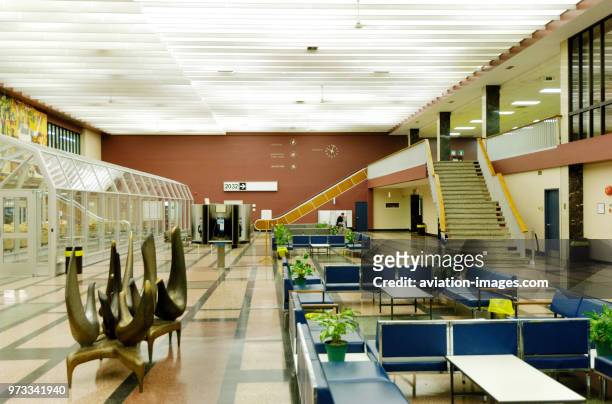 Modern sculpture, seating, stairs, potted-plants, clocks on the wall and Newfoundland Telephone kiosks in the empty terminal.