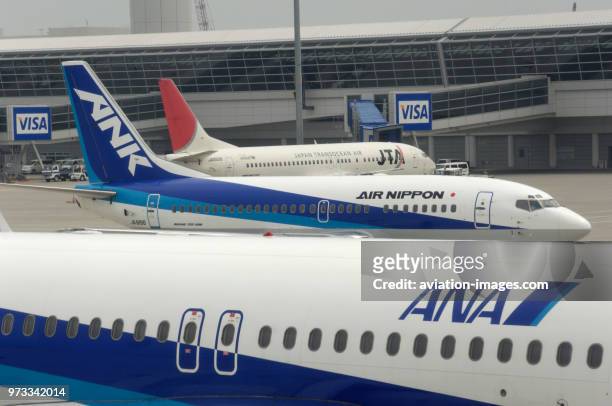An ANA All Nippon Airways Airbus A320-200 with an ANK Boeing 737 taxiing and a JTA B737 parked at the terminal behind.