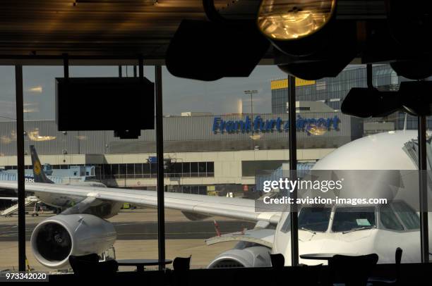 Windshield of the South African Airways Airbus A340 parked at a gate and Lufthansa Boeing 737 parked behind at the terminal seen through a window.