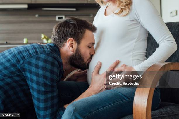 man kissing pregnant woman's baby bump - belly kissing stock pictures, royalty-free photos & images