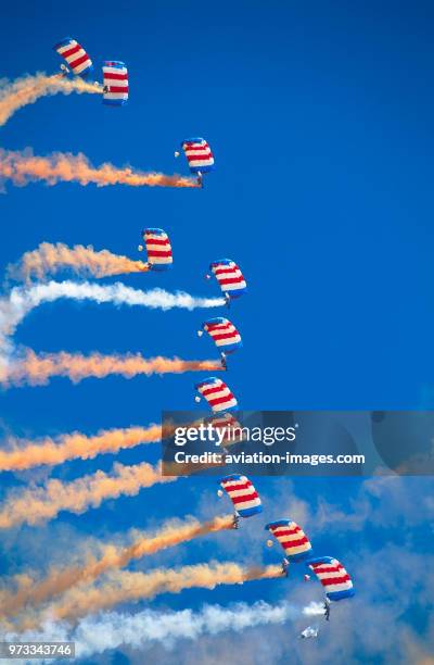 Generic parachute formation team trailing orange and white smoke in a vertical stack.