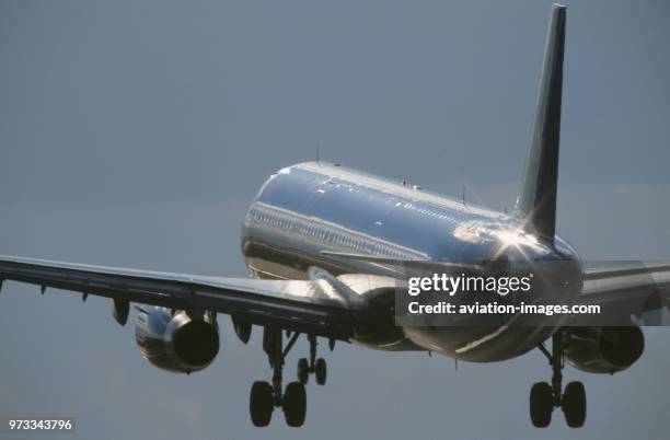 Generic Airbus A321-200 on final-approach with flaps deployed and sun glinting off the fuselage and wings.