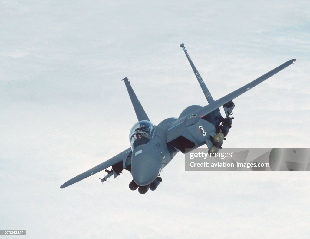 USAF Boeing F-15E Strike Eagle flying enroute above a layer of clouds with a full load of bombs