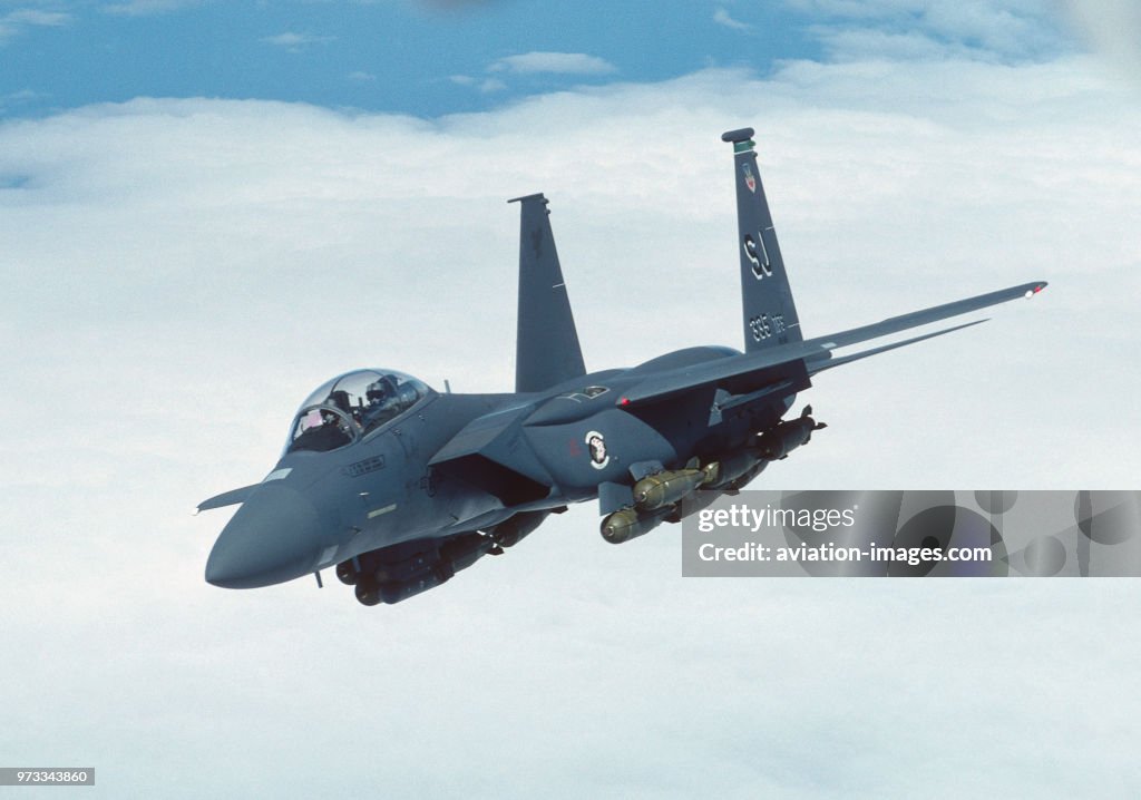 USAF Boeing F-15E Strike Eagle flying enroute above a layer of clouds with a full load of bombs