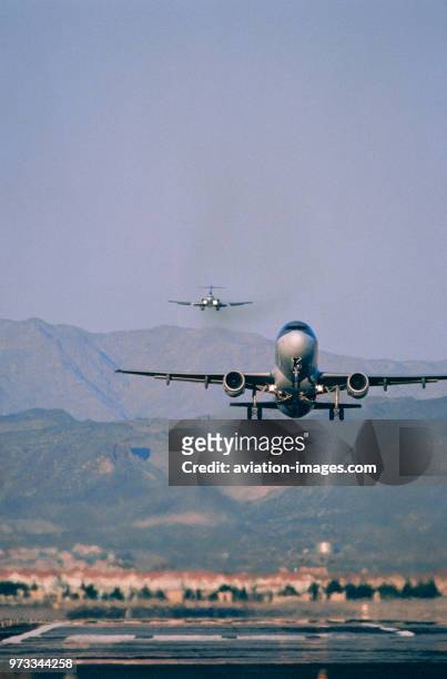 Airbus A320 taking-off with a Boeing 727 on final-approach landing behind over mountains during single runway operations.