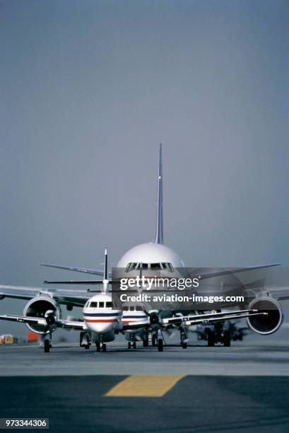 BAe Jetstream J-31s taxiing with a Boeing 767 queueing on a taxiway before take off.