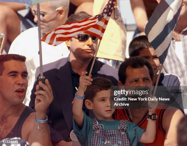 Elian Gonzalez holds American and Cuban flags while sitting on the lap of his great uncle, Lazaro Gonzalez, at the Three Kings Parade in the Little...
