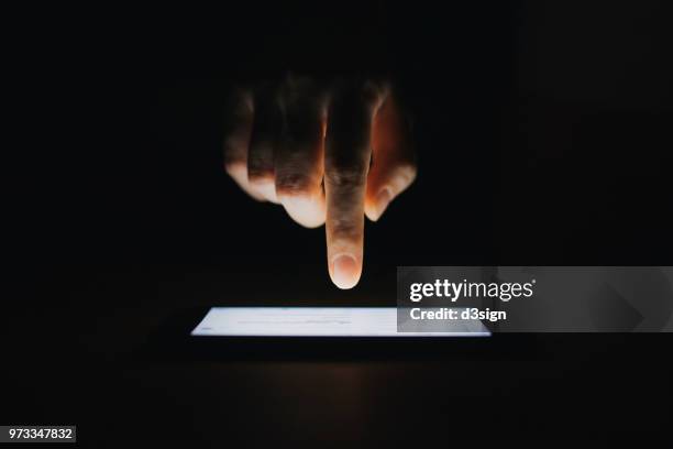 close up of woman's hand checking emails on smartphone  against black background - people on black background stock-fotos und bilder