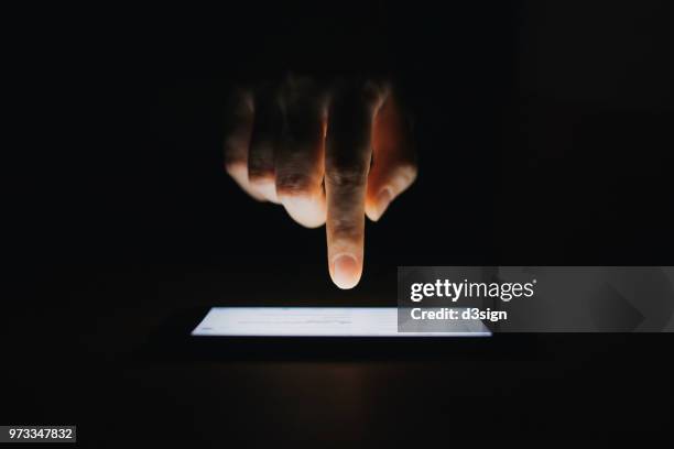 close up of woman's hand checking emails on smartphone  against black background - digital tablet photos et images de collection